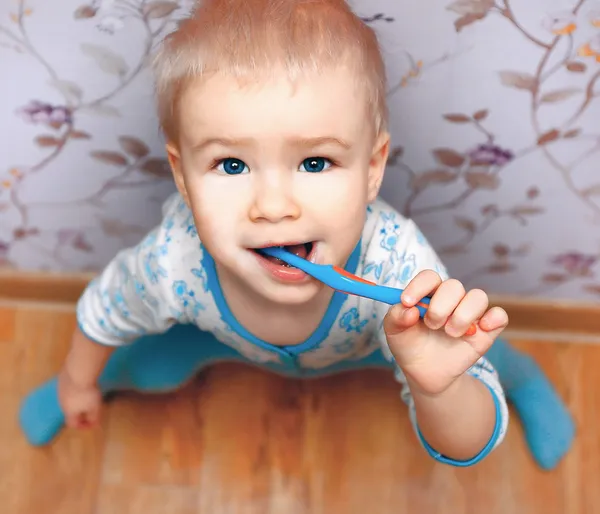 Niño cepillándose los dientes de pie cerca de la pared —  Fotos de Stock