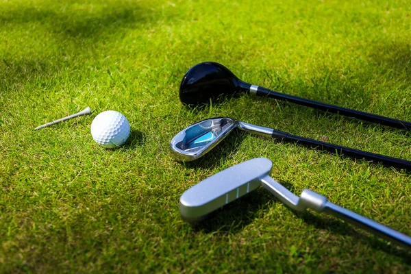 Golfschläger und Ball liegen auf grünem Gras in den Strahlen der ewigen Sonne — Stockfoto