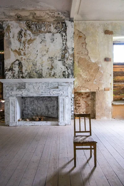 Cadeira em uma sala de estilo loft, lareira no fundo, paredes rasgadas — Fotografia de Stock