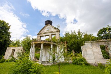 Yeşil ağaçlarla çevrili eski harabe binalar.