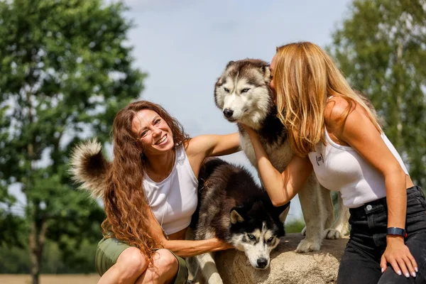 Deux femmes embrassant des chiens husky dans le parc — Photo