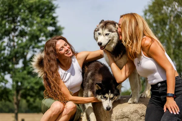 Deux femmes embrassant des chiens husky dans le parc — Photo