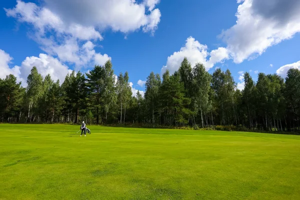 Tájkép, golfpálya, zöld fű az erdő hátterében és fényes égbolt felhőkkel — Stock Fotó