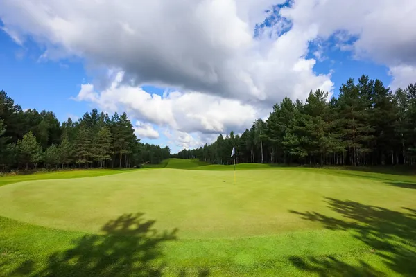 Golf pálya, táj, zöld fű a háttérben egy erdő és egy fényes ég felhők — Stock Fotó