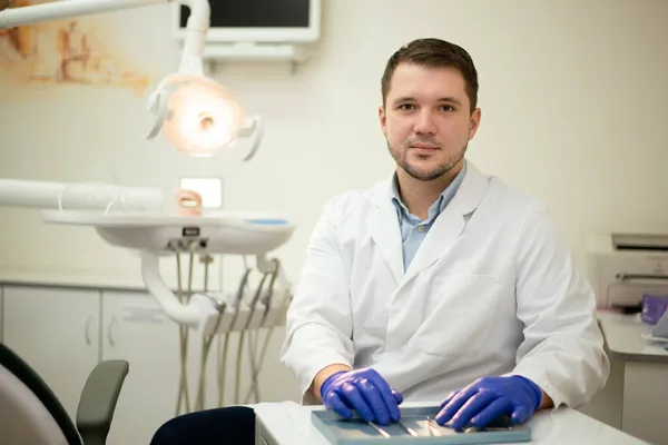 Zahnarzt lächelt und hält ein Werkzeug in der Hand Stockfoto