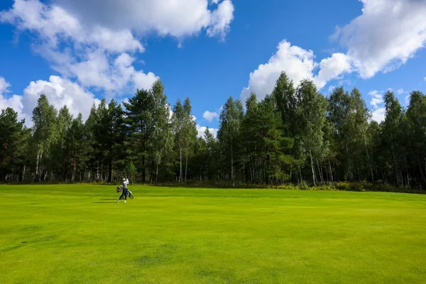 Paisaje, campo de golf, hierba verde en el fondo de un bosque y un cielo brillante con nubes —  Fotos de Stock