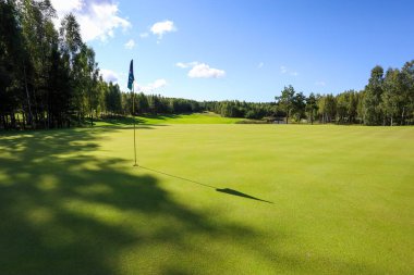 Yeşil çimenli bir golf sahasında bayrak gölgesi