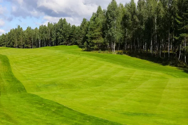 Golf pálya, táj, zöld fű a háttérben egy erdő és egy fényes ég felhők — Stock Fotó
