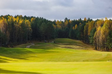 Sonbahar golf sahası, manzara, arka planda yeşil çimenler ve bulutlu parlak bir gökyüzü.