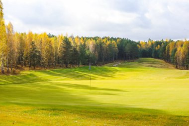 Sonbahar golf sahası, manzara, arka planda yeşil çimenler ve bulutlu parlak bir gökyüzü.