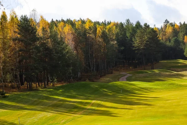 Sonbahar golf sahası, manzara, arka planda yeşil çimenler ve bulutlu parlak bir gökyüzü.