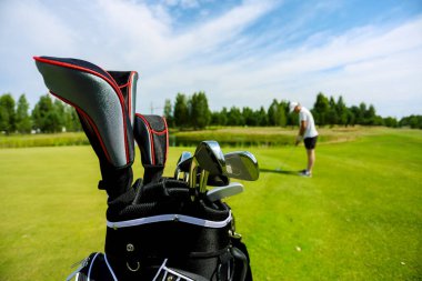 Black golf club bag on a golf course against a background of green grass
