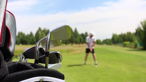 Man tar en golfklubba från en garderob stam och förbereder sig för att träffa bollen — Stockvideo