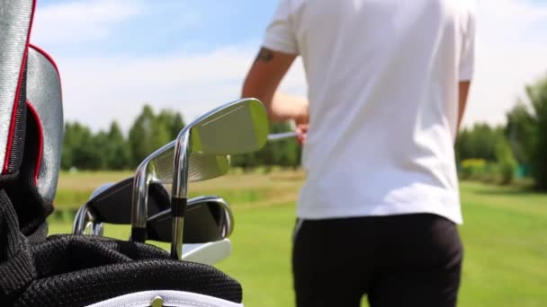 L'homme prend un club de golf d'un coffre de garde-robe et se prépare à frapper la balle — Video