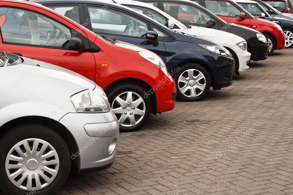 Row of different european marques of used cars for retail sale on a motor dealers forecourt all logos removed