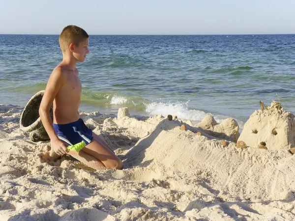 En pojke leker i sanden på stranden — Stockfoto