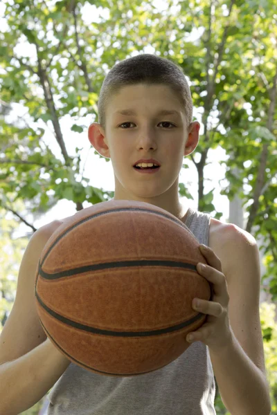 Jovem menino segurando basquete em sua mão — Fotografia de Stock