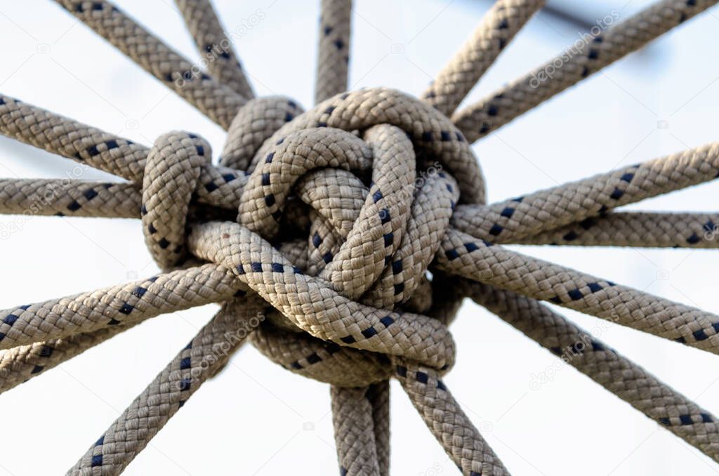 lots of ropes and a big knot against the blue sky close up