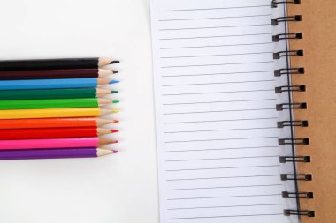 Renkli kalemler ve beyaz arkaplan üzerinde kalem olan not defterleri