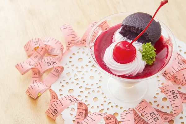 Cherry cheesecake with macaron and measurements tape — Stock Photo, Image