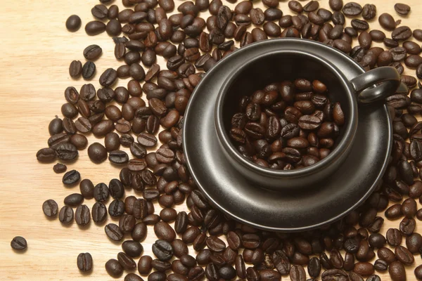 Grão de café em xícara de café preto — Fotografia de Stock