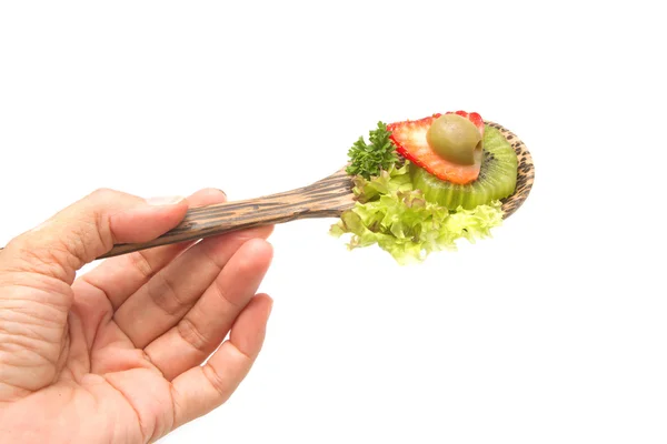 Mano sosteniendo cuchara de madera con aislado de ensalada de frutas —  Fotos de Stock