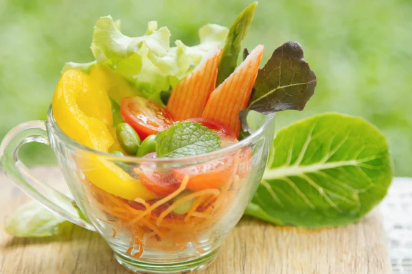 Салат из свежих овощей в прозрачной чаше на зеленой природе — стоковое фото