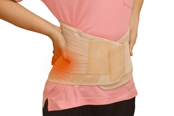 Woman in pain from back injury wearing lumbar brace corset — Stock Photo, Image