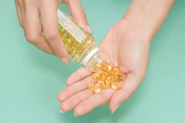 Vrouw hand nemen vitamine vis van omega-3 olie pillen — Stockfoto