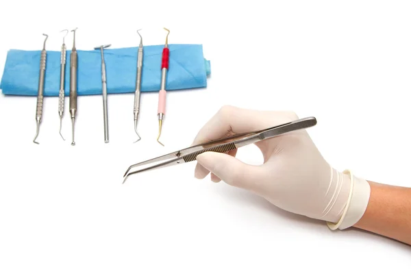 Tandläkare hand och dental verktyg på vit bakgrund — Stockfoto