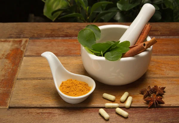 Mortar and pestle with herb and pills on wood texture — Stock Photo, Image