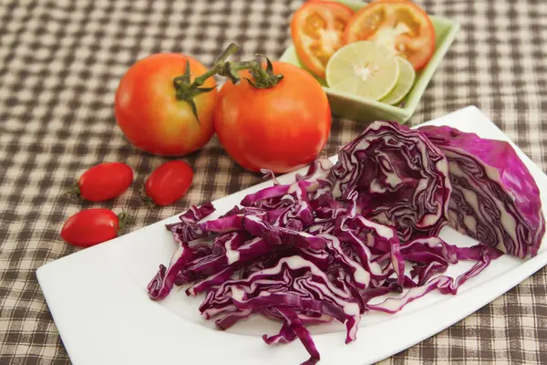 Rode kool slice op witte plaat met rode tomaten — Stockfoto