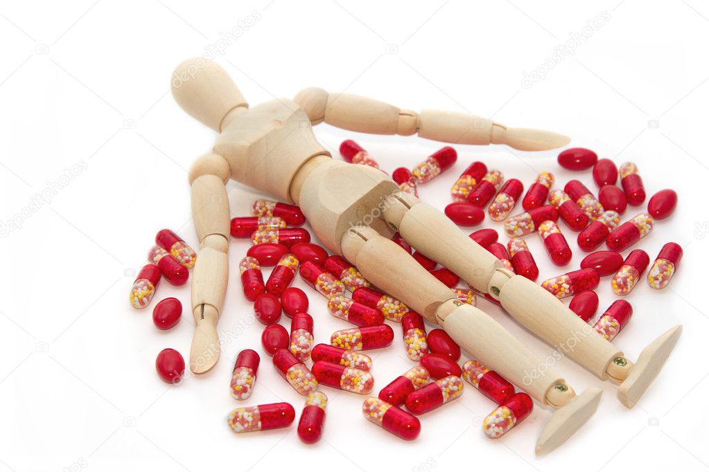 wooden model dummy lying over pile of pills