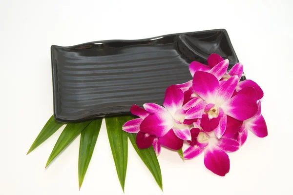 Пустая черная тарелка с орхидеей — стоковое фото