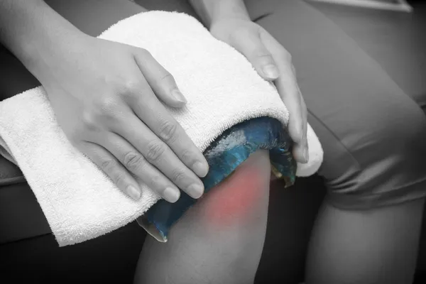 A woman applying cold pack on swollen hurting knee after accide — Stock Photo, Image