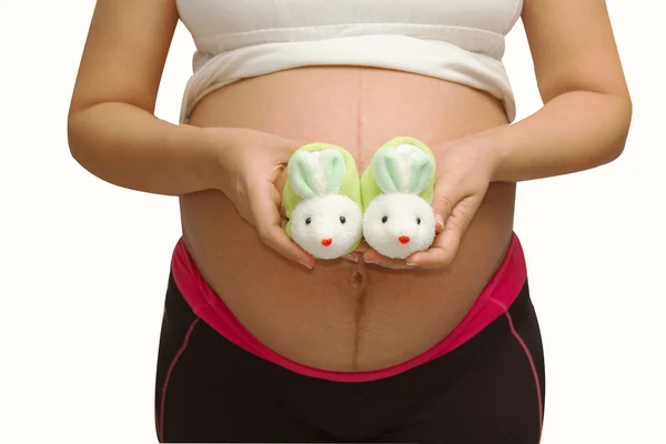 Kleine Schuhe für das Ungeborene im Bauch einer Schwangeren — Stockfoto