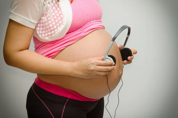 Pancia di donna incinta e cuffie — Foto Stock