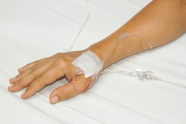 IV solution in a patients hand,saline drip — Stock Photo, Image