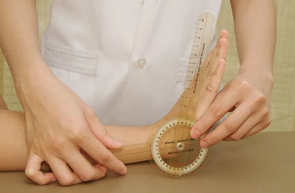 Physiotherapeut untersucht Handgelenk von Patienten mit Goniometer — Stockfoto