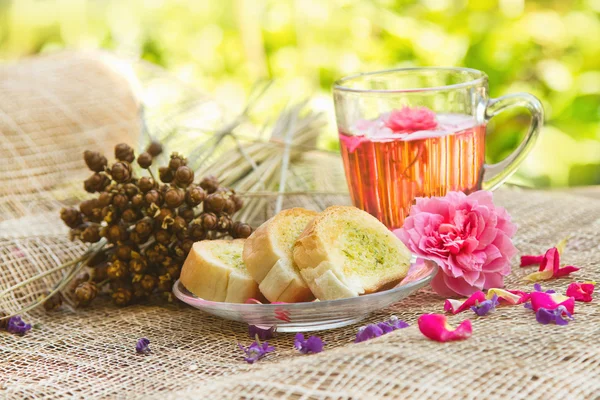 Rosa te och hembakade vitlöksbröd på bord i trädgården, efter — Stockfoto