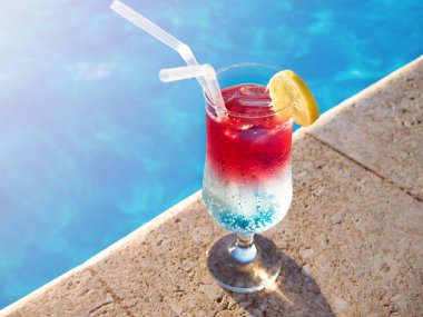 Yüzme havuzunun arka planında taze bir kokteyl olan güzel bir bardak. Yukarıdan bak, açık hava, yakın plan. Tatil ve seyahat kavramı