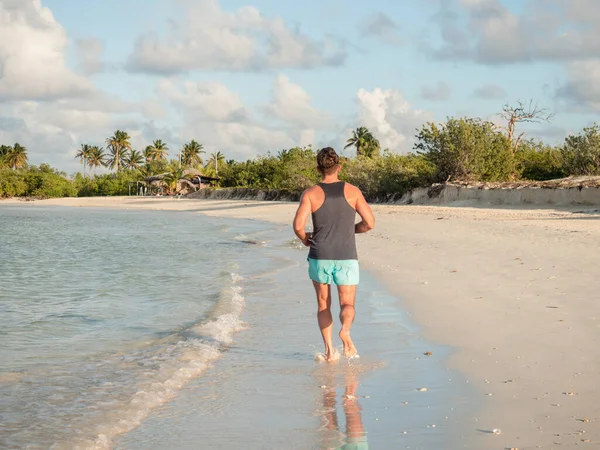 Genç adam Atlantik Okyanusu kıyısında koşuyor.