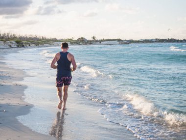 Genç adam Atlantik Okyanusu kıyısında koşuyor.