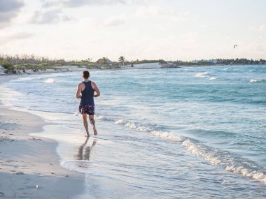 Genç adam Atlantik Okyanusu kıyısında koşuyor.