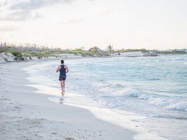 Genç adam Atlantik Okyanusu kıyısında koşuyor.