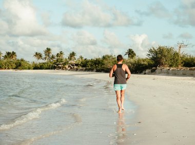 Genç adam Atlantik Okyanusu kıyısında koşuyor.