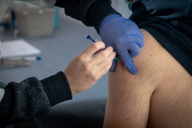 İsrail, Ashkelon 13 Ocak 2021. Doktor hastaya koluna bir iğne yapar. Nüfusun tehlikeli hastalıklara karşı toplu aşılanması kavramı, COVID-19