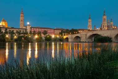 Zaragoza, İspanya. Mayo 2022. Ti Basilika ti Apo ti Adigitayo ken ti daan a bato a rangtay manipud iti kasungani a bangir a bumallasiw iti karayan Ebro. Napintas a buyaiti agsapa iti parbangon
