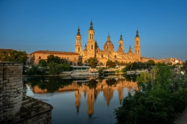 Zaragoza, İspanya. Mayo 2022. Ti Basilika ti Apo ti Adigitayo ken ti daan a bato a rangtay manipud iti kasungani a bangir a bumallasiw iti karayan Ebro. Napintas a buyaiti agsapa iti parbangon