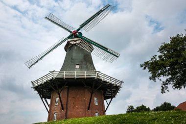 Kanalın yanında büyük bir rüzgar gülü ve bulutlu bir gökyüzü.